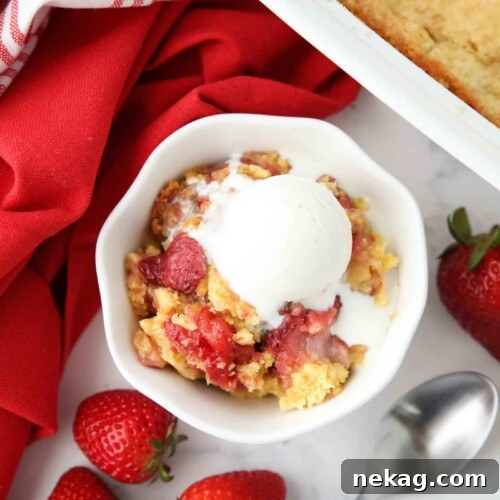 Strawberry dump cake made with fresh strawberries in a bowl with ice cream on top.
