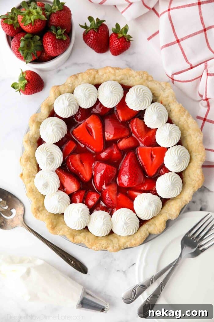 Top view of fresh strawberry pie with jello glaze and whipped cream.