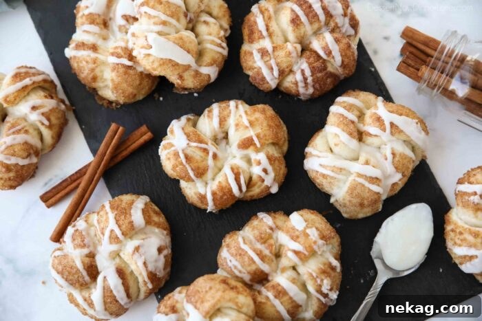 A wide shot of glazed cinnamon knots beautifully arranged on a dark slate serving board, emphasizing their golden color and tempting drizzle.