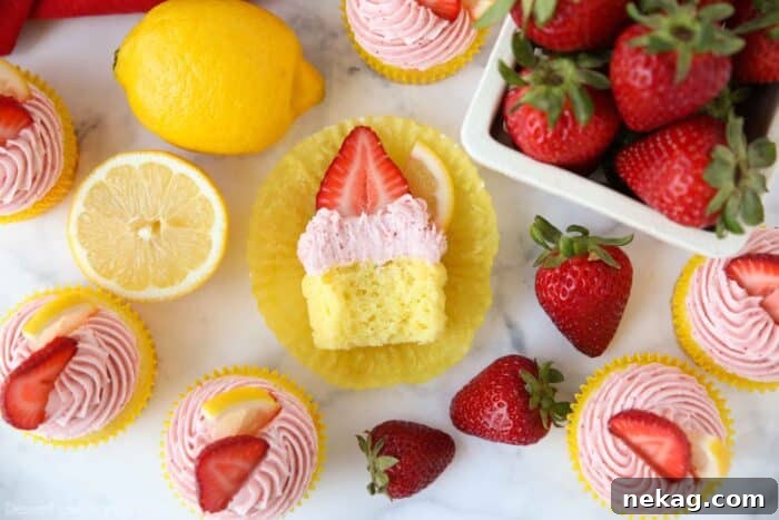 Sunshine Strawberry Lemonade Cupcakes 14 Strawberry lemonade cupcake with a bite taken out showing the inside of a fluffy lemon cupcake with strawberry frosting.