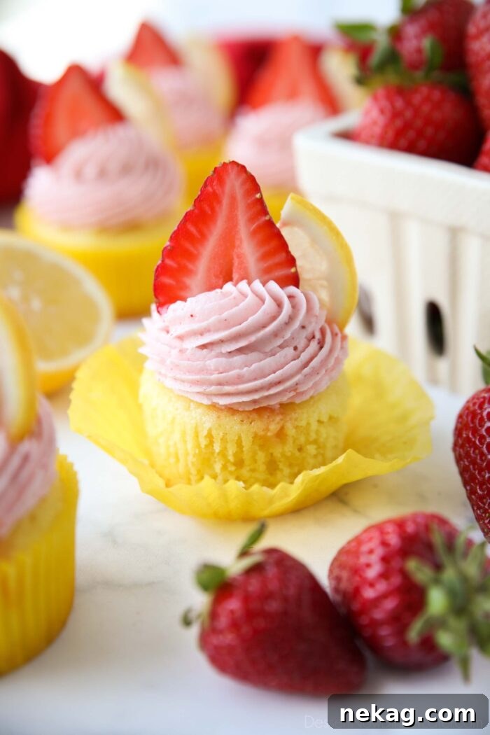 Sunshine Strawberry Lemonade Cupcakes 5 Wrapper pulled down from a lemonade cupcake topped with strawberry frosting.