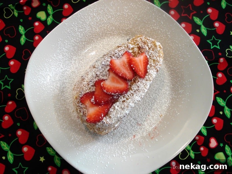 A stack of Crispy Strawberry & Greek Yogurt Stuffed French Toast with powdered sugar and fresh strawberries.