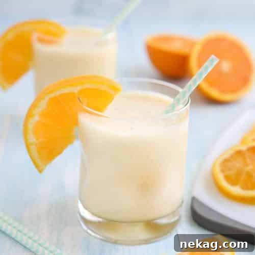 Orange Julius smoothie in a cup with a straw and fresh orange slices.
