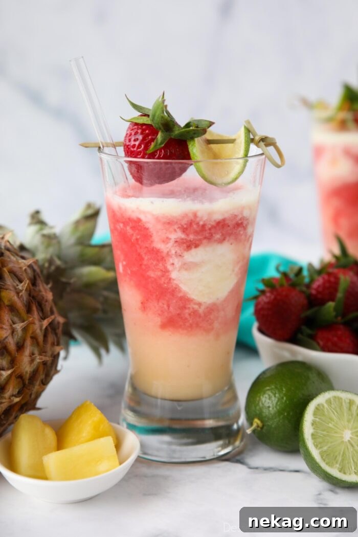 Vibrant Virgin Miami Vice Refresher 2 Virgin Miami Vice Drink in a tall glass with a strawberry and lime garnish, showcasing vibrant red and white layers.
