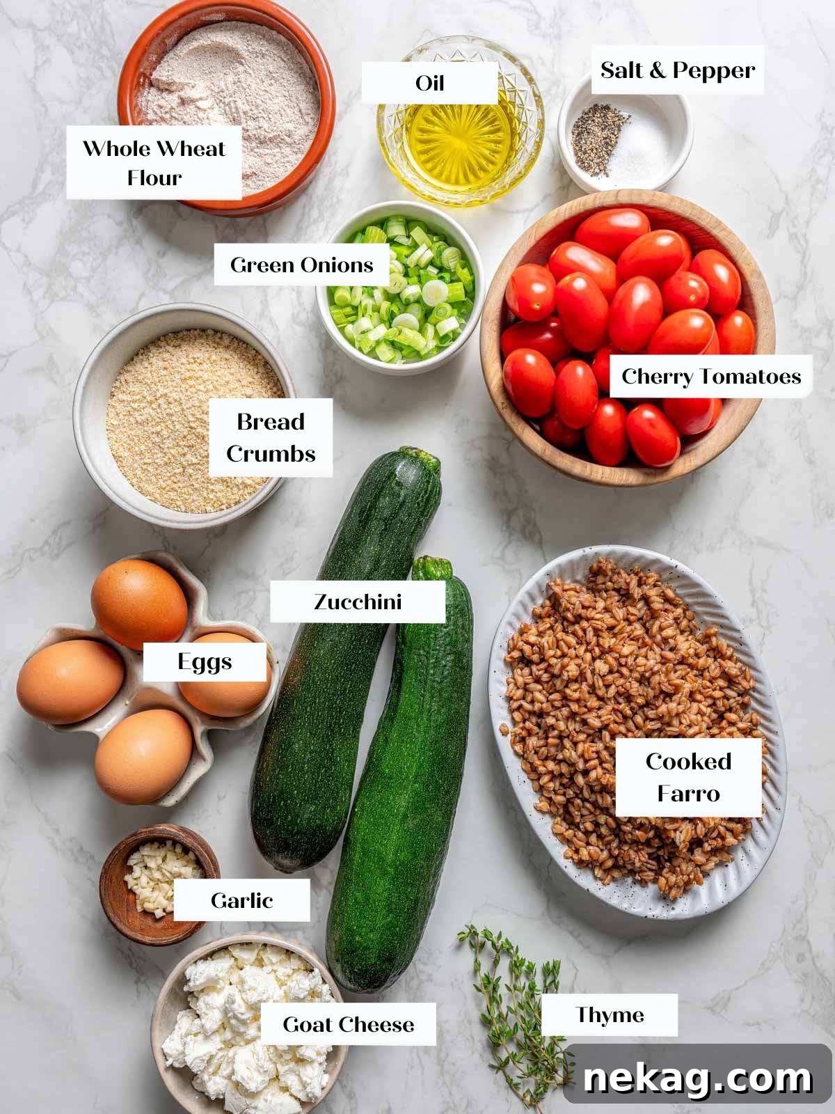 A beautiful arrangement of fresh zucchini fritter ingredients on a marble surface, including zucchini, farro, breadcrumbs, green onions, eggs, and herbs.