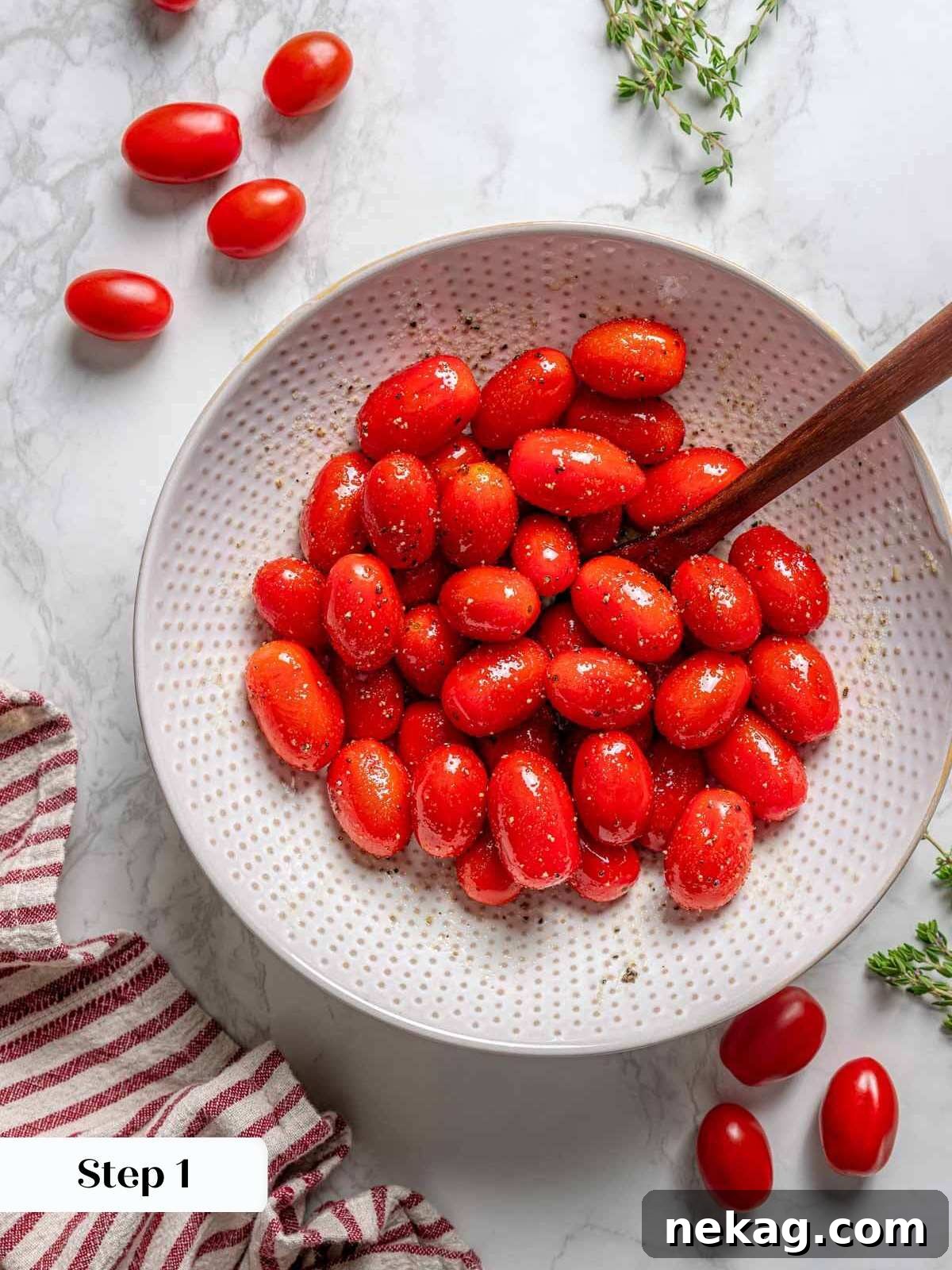 Fresh cherry tomatoes in a bowl, glistening with oil and seasoning, ready for roasting.