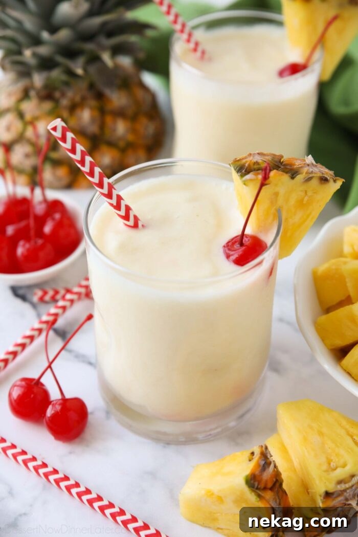 Virgin pina colada in a glass cup with a wedge of pineapple, a maraschino cherry, and a straw.