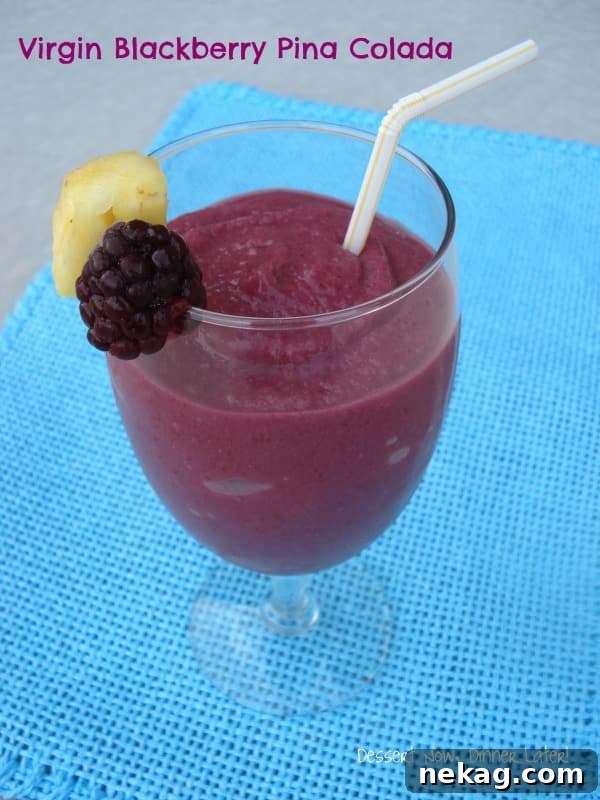 Virgin Blackberry Pina Colada in a glass garnished with a fresh pineapple chunk and blackberry.