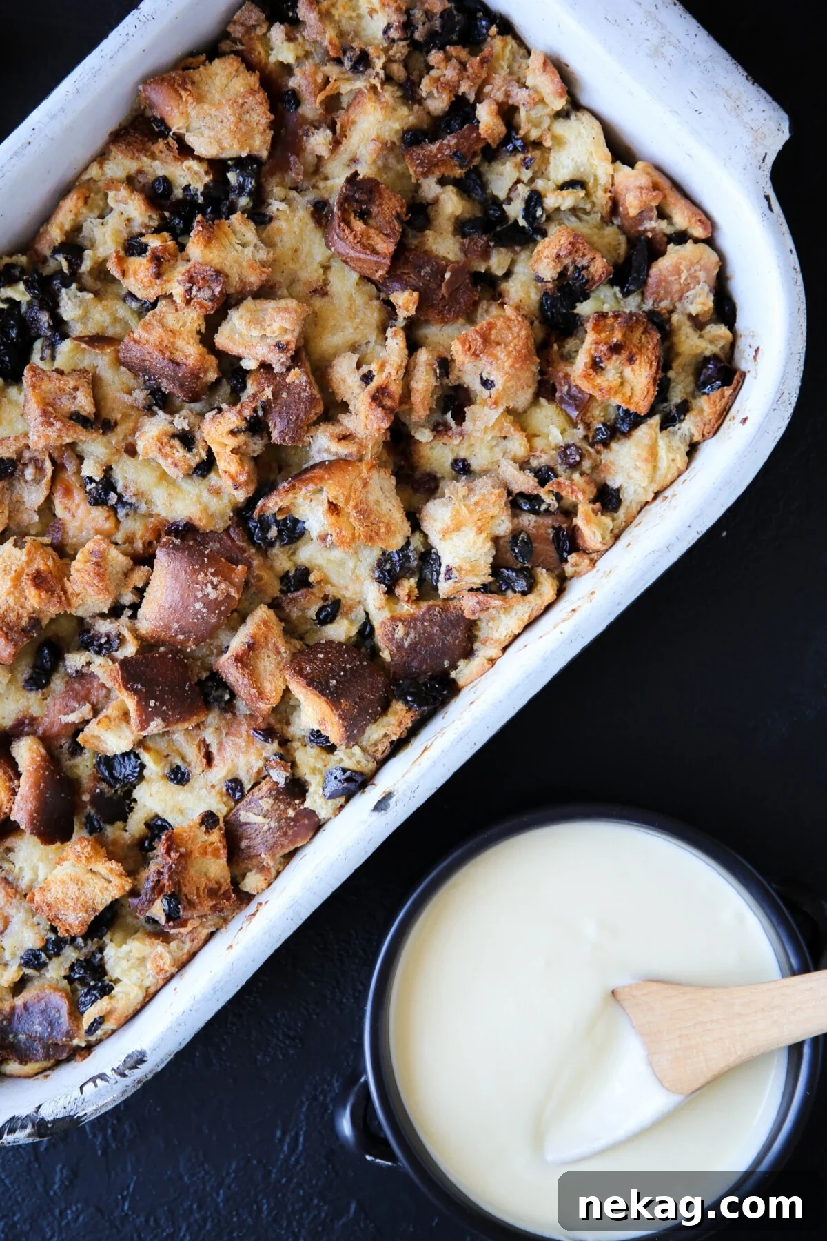 Golden brown bread pudding baked to perfection in a vintage metal serving dish, ready for a generous serving.