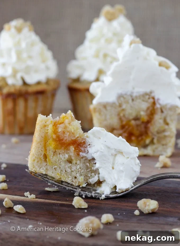 Close-up of freshly baked Peach Crisp Cupcakes showcasing the compote filling and creamy Swiss meringue buttercream