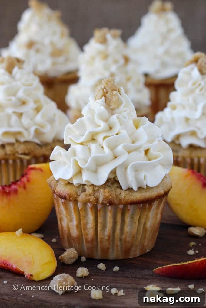 Cross-section view of a Peach Crisp Cupcake revealing the hidden peach compote filling and fluffy frosting