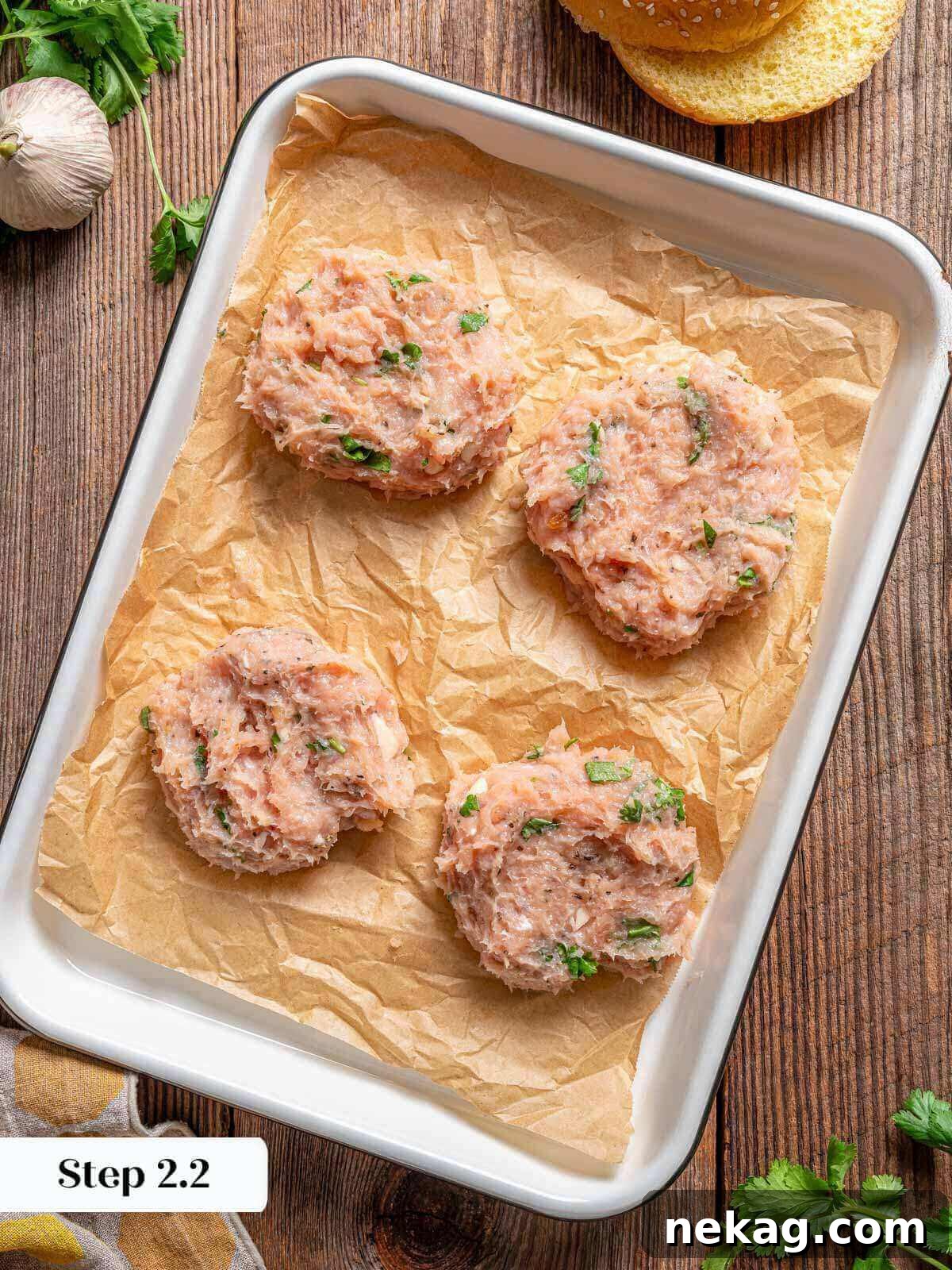 Ultimate Chicken Burgers 6 shaped chicken patties arranged neatly on a parchment-lined baking sheet.
