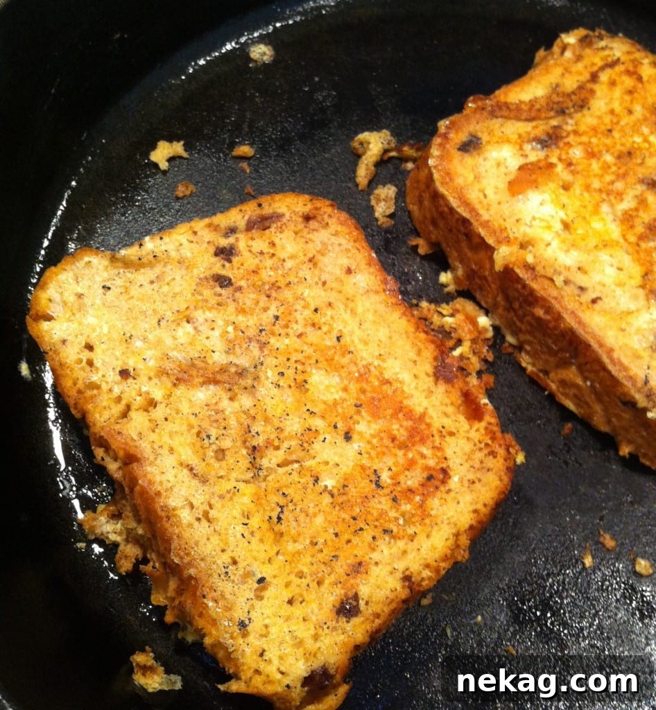 A stack of Cinnamon Raisin French Toast, perfectly cooked and lightly dusted with powdered sugar.