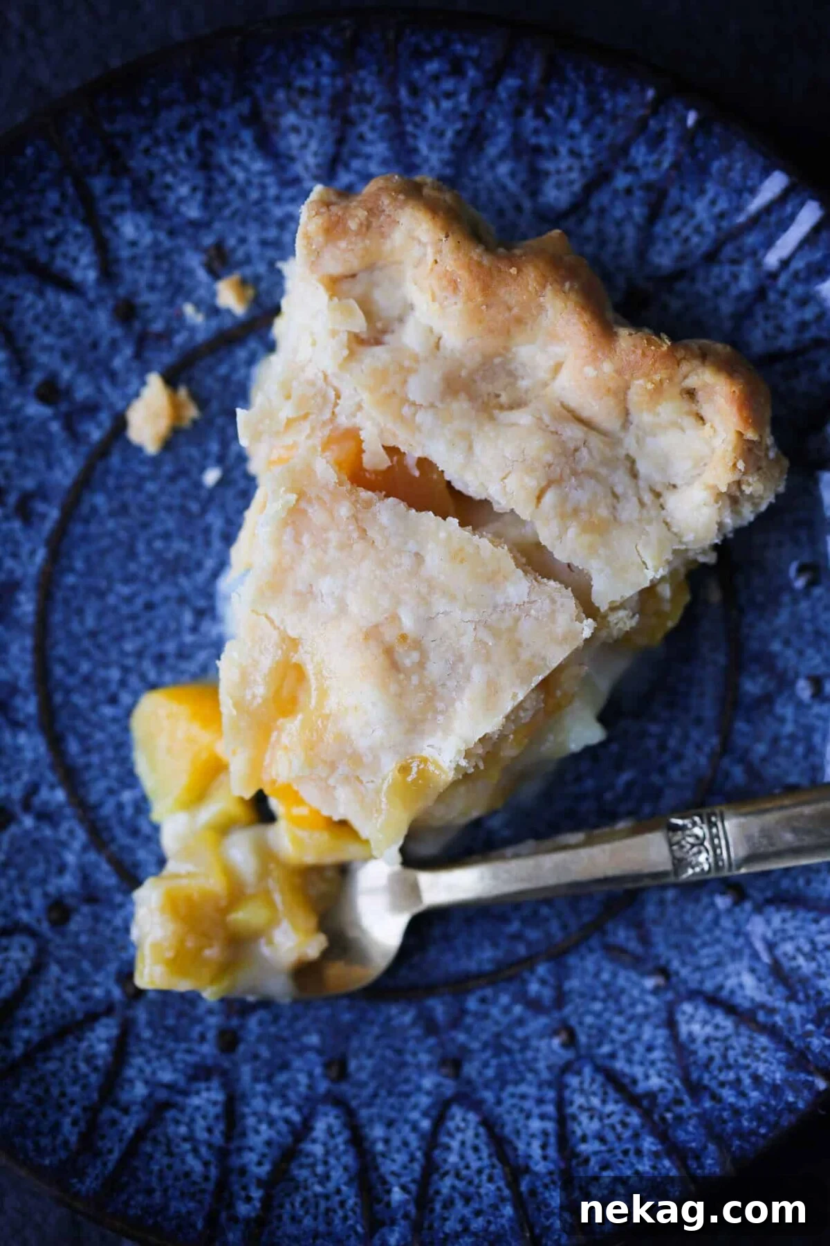 A generous slice of old-fashioned peach pie, showcasing its flaky crust and juicy filling.
