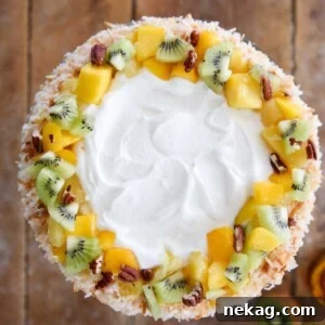 Tropical Fruit Trifle, decorated with fresh fruit, pecans, and coconut, ready to serve.