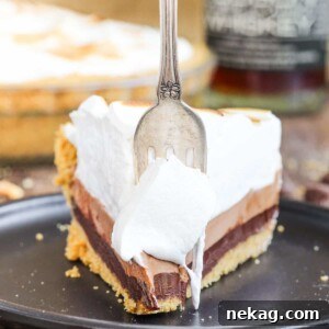 No bake whiskey s'mores pie with antique fork, showcasing its rich layers.