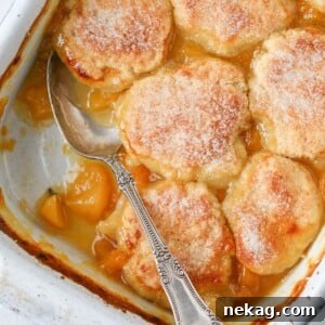 An Old Fashioned Peach Cobbler baked to perfection, with a vintage spoon ready for serving.