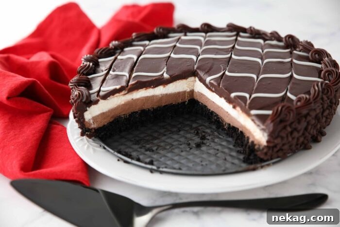 Copycat Black Tie Mousse Cake missing a couple of pieces to show layers of chocolate cake, chocolate mousse, vanilla mousse, with swirled white and dark chocolate ganache on top.