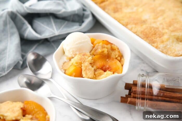 Peach dump cake (aka peach cobbler with cake mix) in a bowl with a scoop of vanilla ice cream.