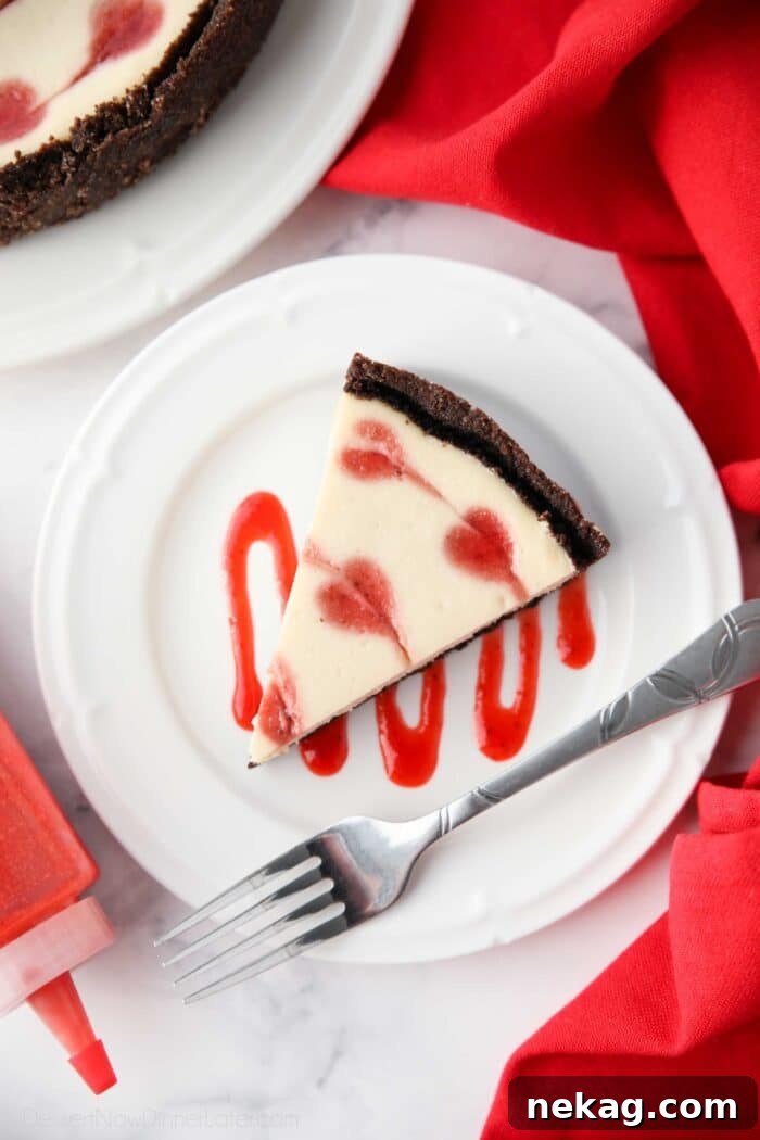 Velvet Heart Cheesecake 9 A slice of Valentine's Day Cheesecake with red hearts baked into the batter, served on a plate with strawberry sauce drizzled artfully.