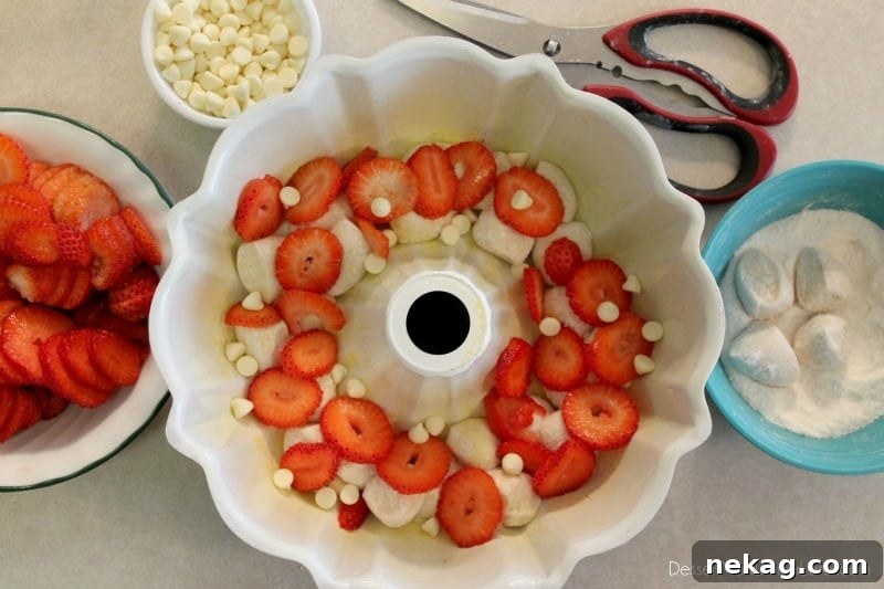 Layers of dough, strawberries, and white chocolate chips in a bundt pan before baking