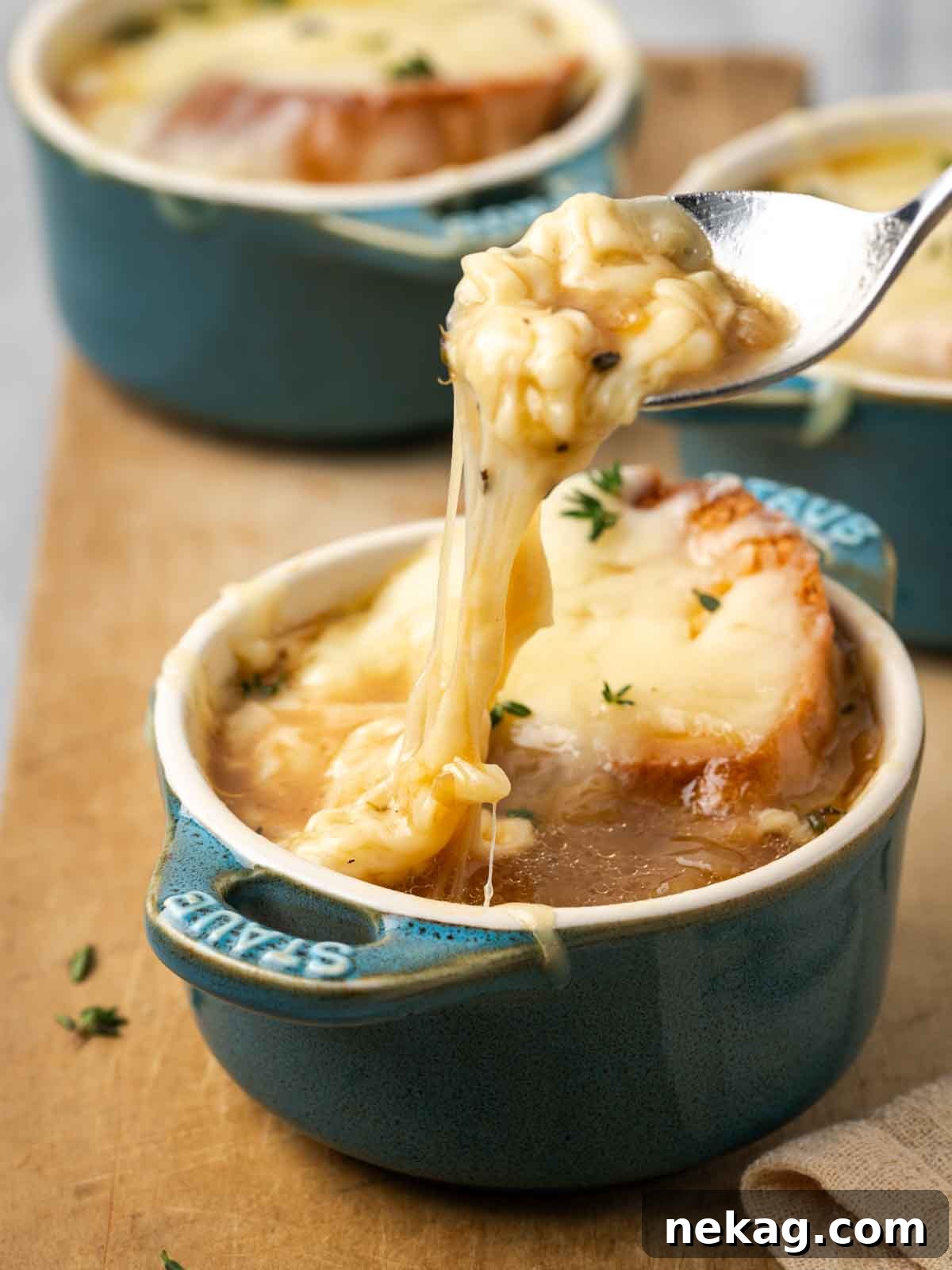 Quintessential French Onion Soup 2 cheese pull from hot french onion soup, showcasing the melted cheese and toasted bread.