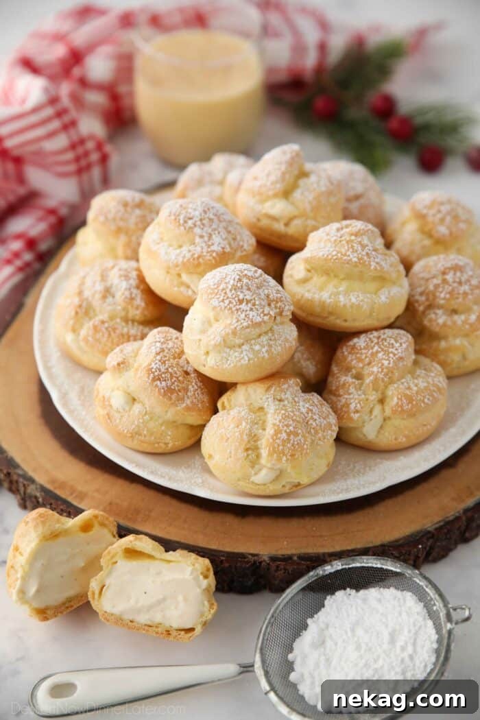 Holiday Eggnog Cream Puffs 2 Delicate cream puffs overflowing with fluffy whipped eggnog pastry cream, ready for holiday festivities.