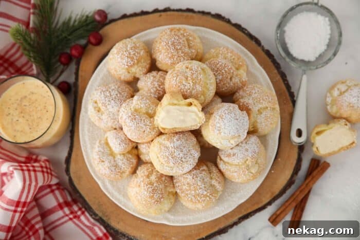 Holiday Eggnog Cream Puffs 13 Top-down view of beautifully arranged eggnog cream puffs on a serving plate, one cut open to show the creamy filling.
