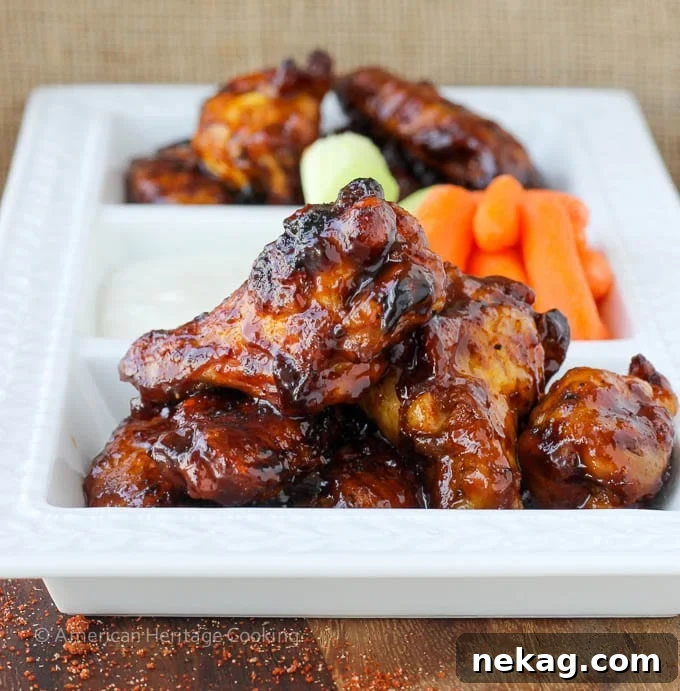 Sweet Heat Crispy Baked Wings 5 Plated chicken wings with a side of carrots on a white plate, ready to be enjoyed.