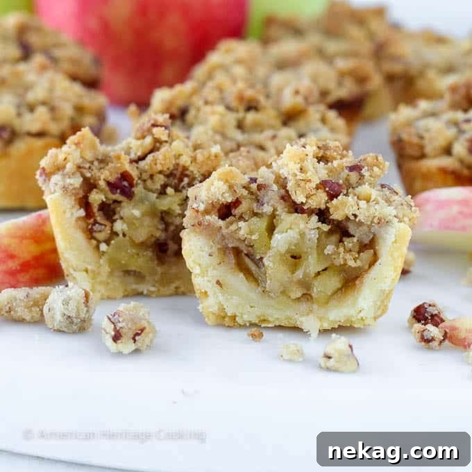 Handheld Apple Delights 4 cream cheese crust with apple pie filling half on white surface.
