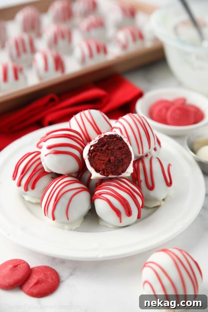 Decadent Red Velvet Bites 2 Exquisite Red Velvet Truffles arranged beautifully on a plate, with one truffle sliced open to reveal its vibrant red cake interior encased in a crisp white chocolate shell.