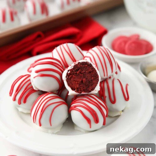 Decadent Red Velvet Bites 11 A featured image of Red Velvet Truffles on a plate with one cut open showing the red cake inside of the white chocolate shell.