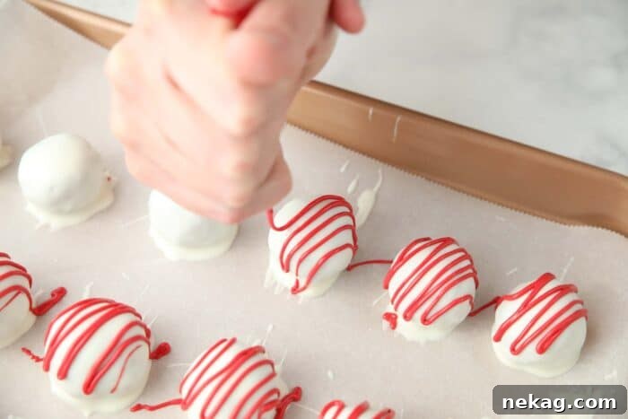 Decadent Red Velvet Bites 8 The process of elegantly piping melted red candy melts over pristine white chocolate-covered red velvet truffles, creating beautiful decorative streaks.