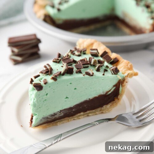 Decadent Chocolate Mint Dream 11 Slice of chocolate mint pie on a plate with layers of pastry crust, chocolate ganache, mint no bake cheesecake, and chopped Andes mints.
