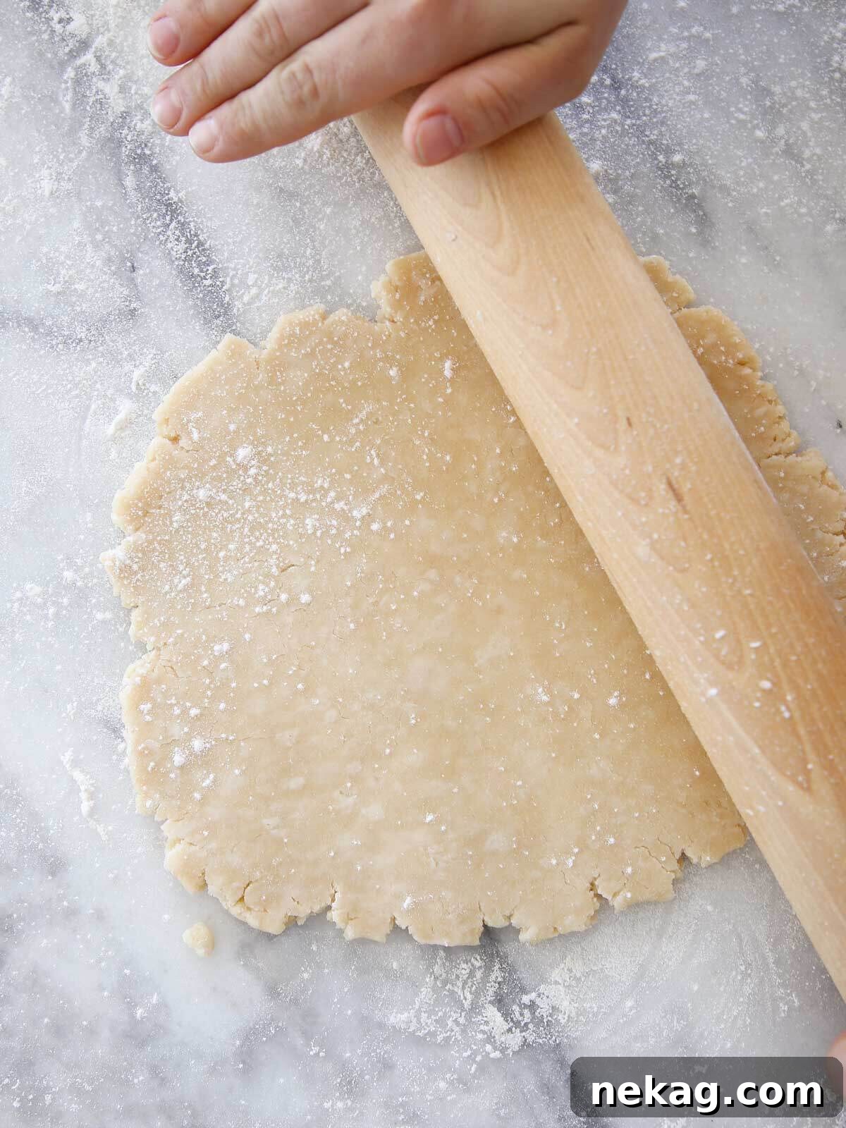 Flaky Crisco Pie Crust Recipe 2 Crisco pie dough being rolled with a rolling pin on a floured surface, ready for the pie dish.