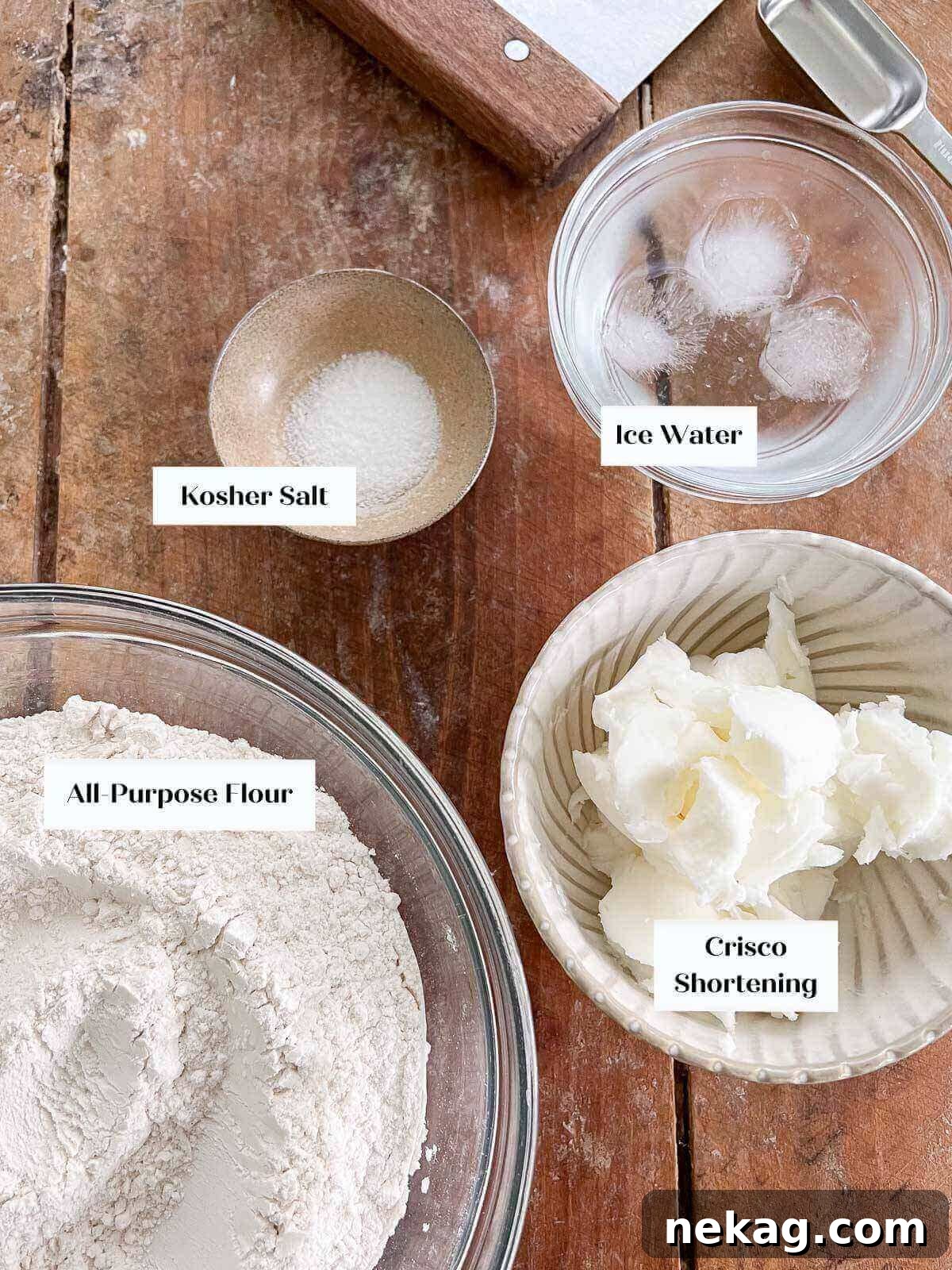 Flaky Crisco Pie Crust Recipe 5 Crisco pie crust ingredients, including flour, salt, frozen shortening, and a glass of ice water, laid out on a wooden surface.