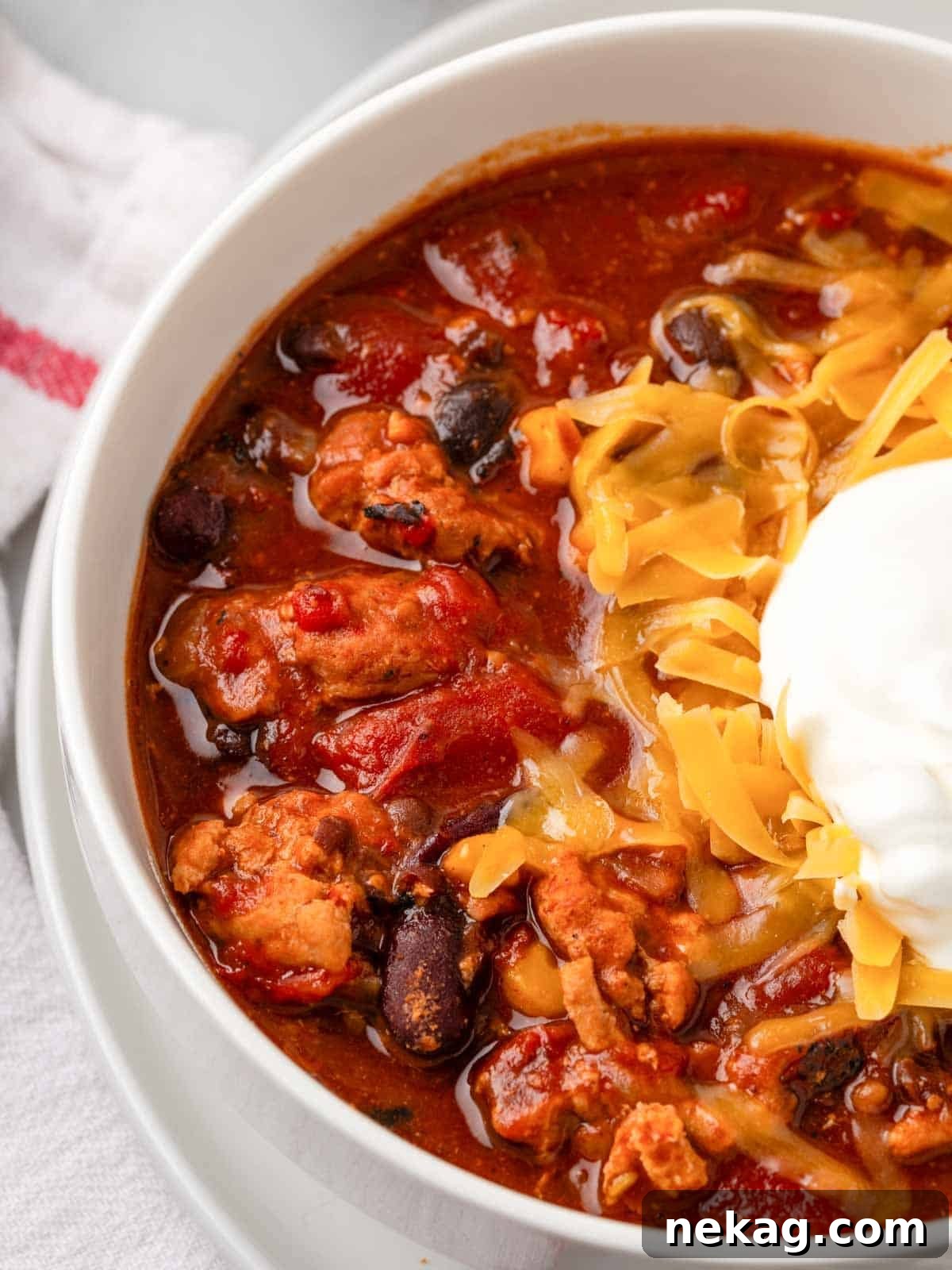 A vibrant bowl of chipotle chili with beans, garnished with a dollop of sour cream and a sprinkle of shredded cheese, invitingly presented.