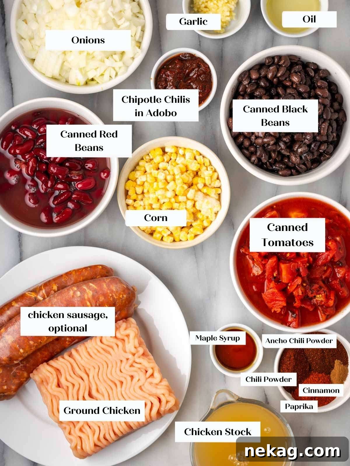 Arrangement of fresh chicken chili ingredients on a white marble countertop, showcasing quality and freshness.