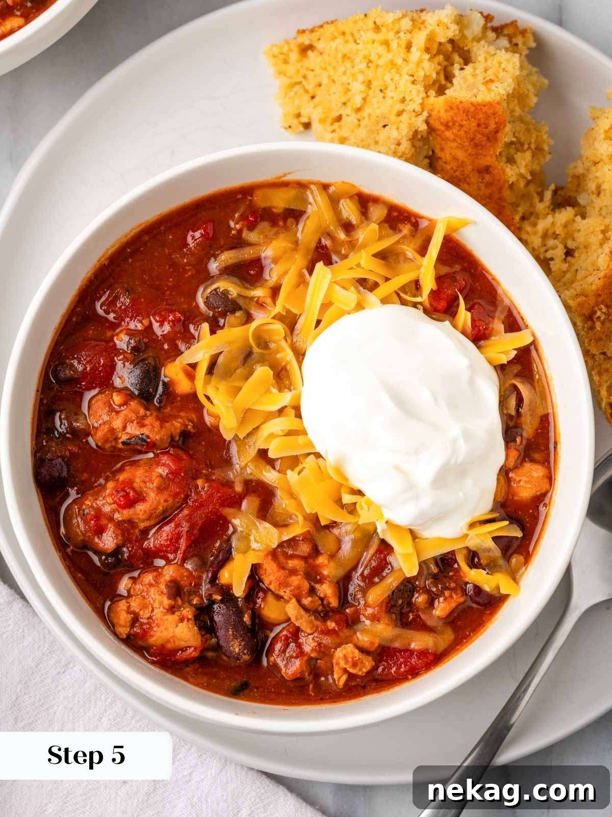A beautifully presented bowl of chipotle chili, generously topped with cool sour cream and shredded cheese.