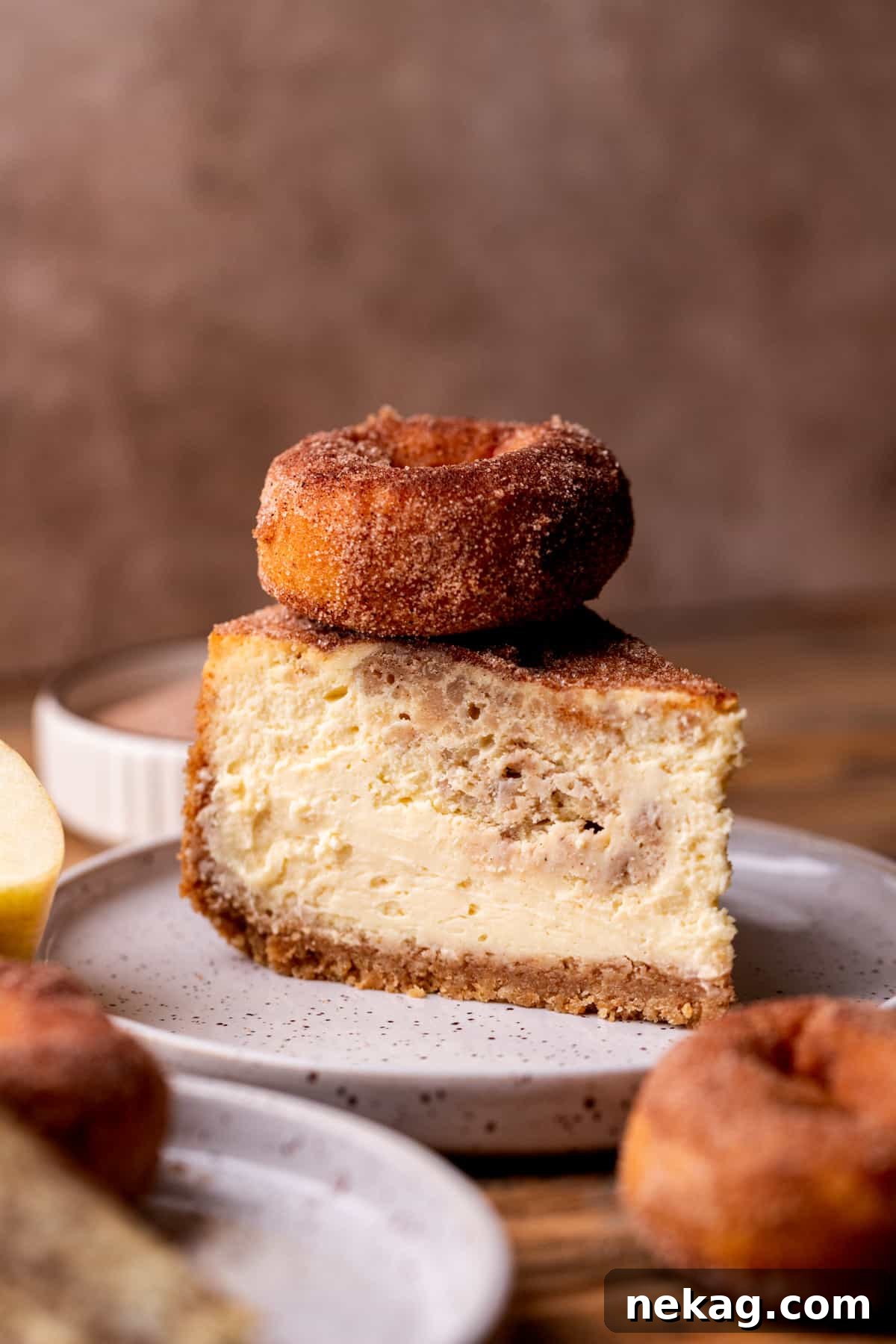 A luscious slice of apple cider cheesecake, topped with a mini donut, highlighting its creamy texture and rich toppings.