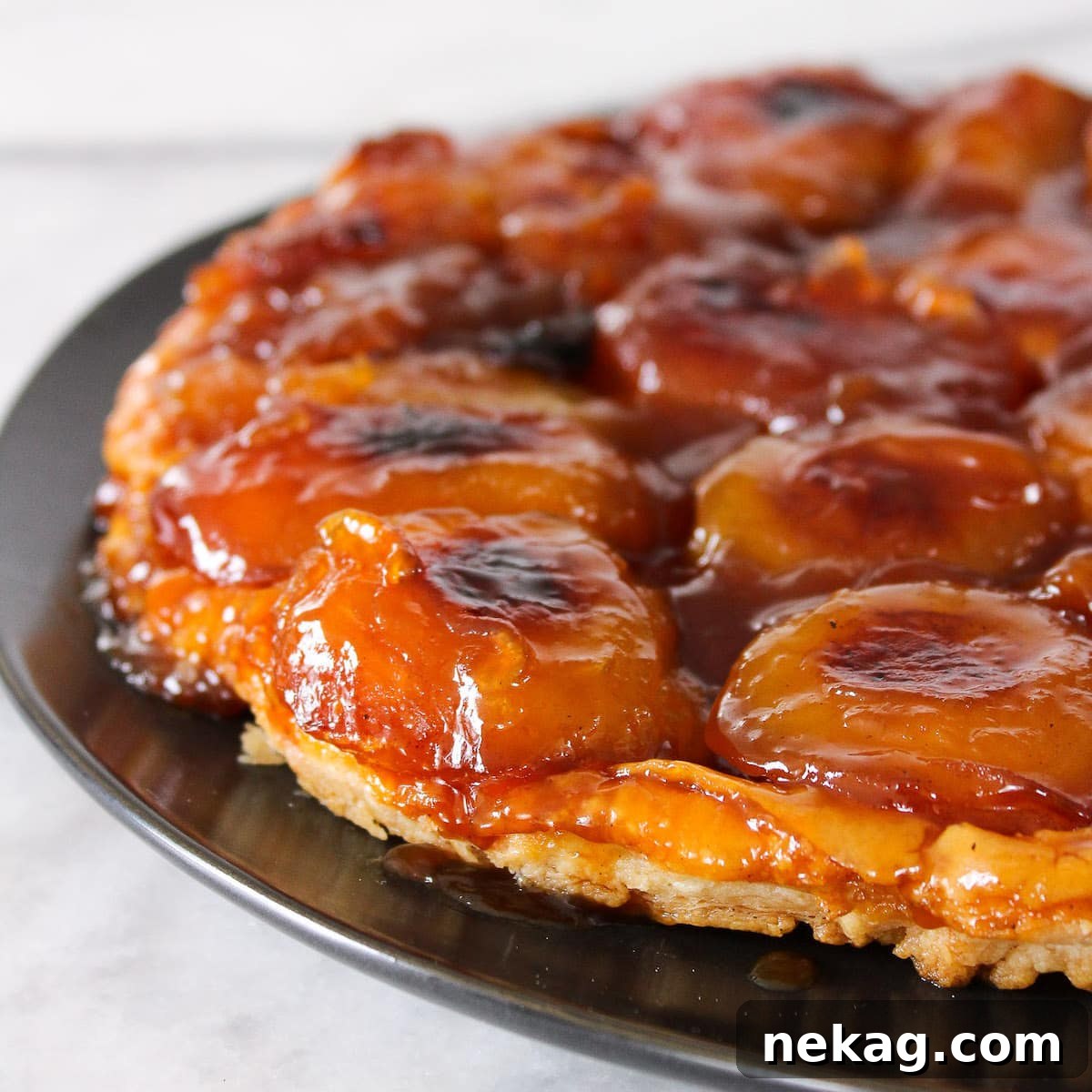 A decadent Apple Tarte Tatin served on a elegant black plate, showcasing its golden caramel and tender apples.