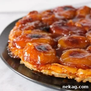 Apple Tarte Tatin beautifully presented on a sleek black plate, showcasing its golden crust and caramelized apples.