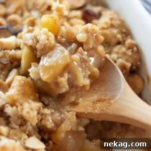 A scoop of ginger spiced apple crumble in a bowl, with a rich, golden topping.