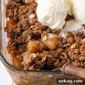 A dish of baked apple crisp being served, highlighting its bubbly apple filling and crunchy topping.