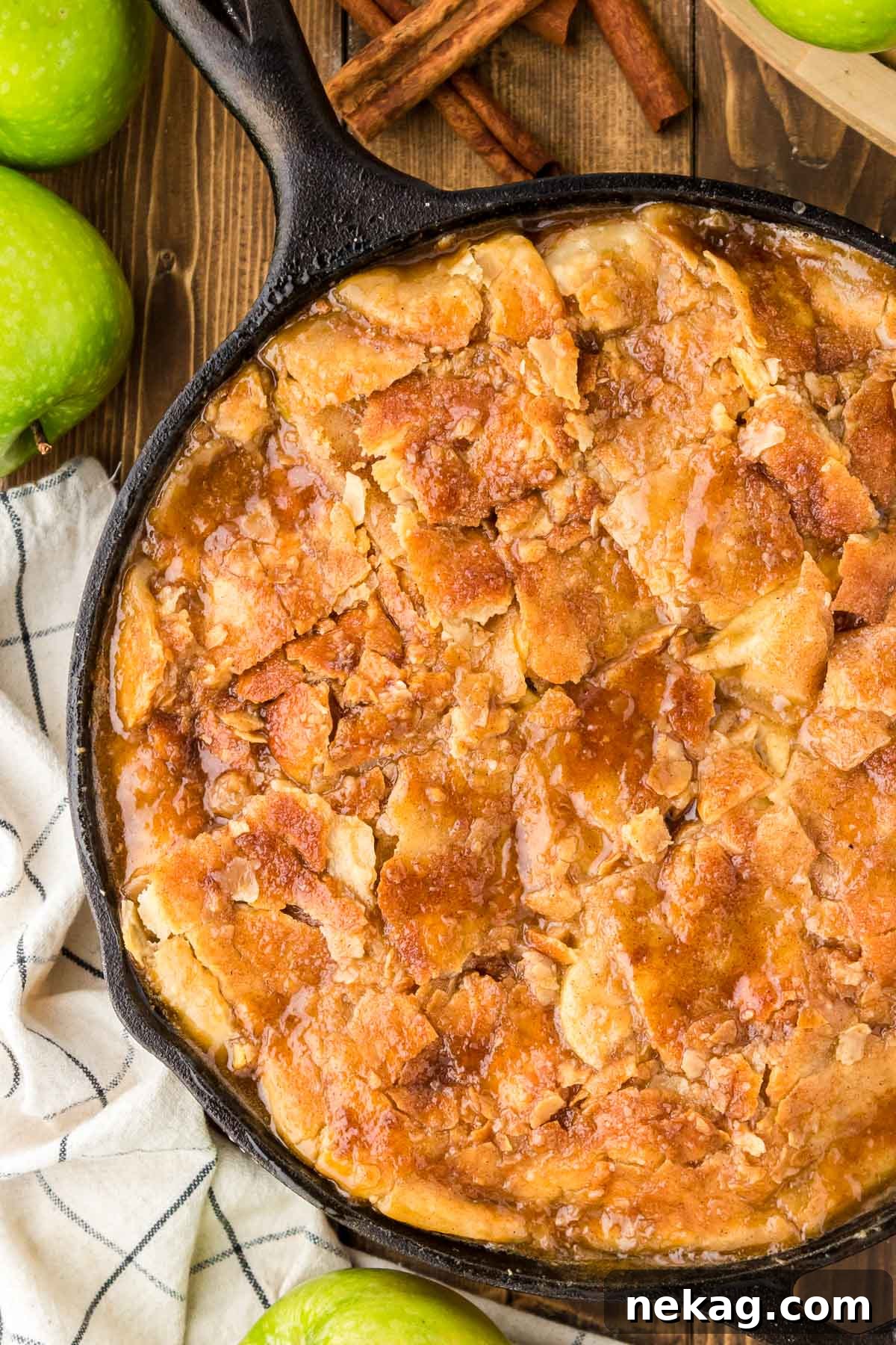 A rustic baked apple pandowdy in a cast-iron skillet, topped with a golden-brown crust.