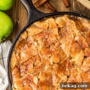 A sliced apple pandowdy in a cast-iron skillet, showing the broken crust and tender apple filling.