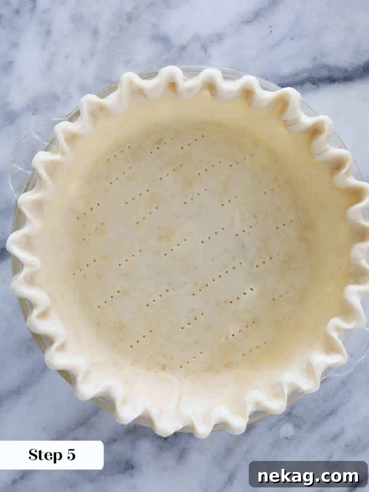 Mastering Blind Baking for a Perfect Pie Crust 7 A lined, fluted, and docked unbaked pie crust in a metal tin, ready for baking.