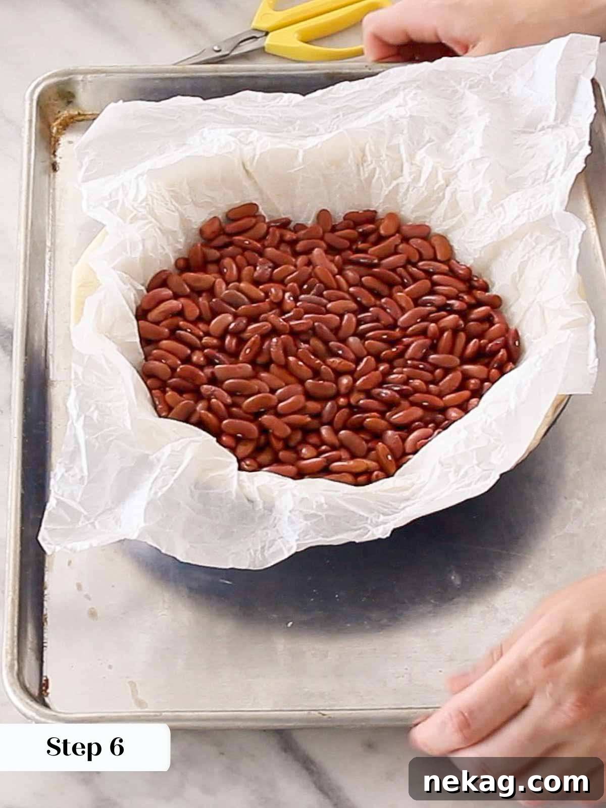 Mastering Blind Baking for a Perfect Pie Crust 8 Parchment paper and baking beans inside a par-baked pie crust in a metal tin.