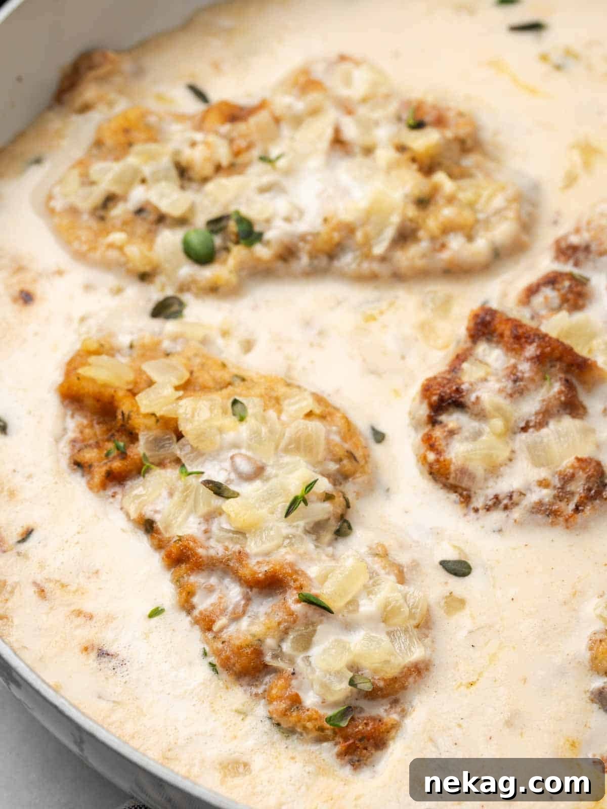Creamy Mushroom Smothered Pork Chops 2 Close-up of mushroom pork chop in a pan, smothered in creamy sauce and garnished with fresh thyme.