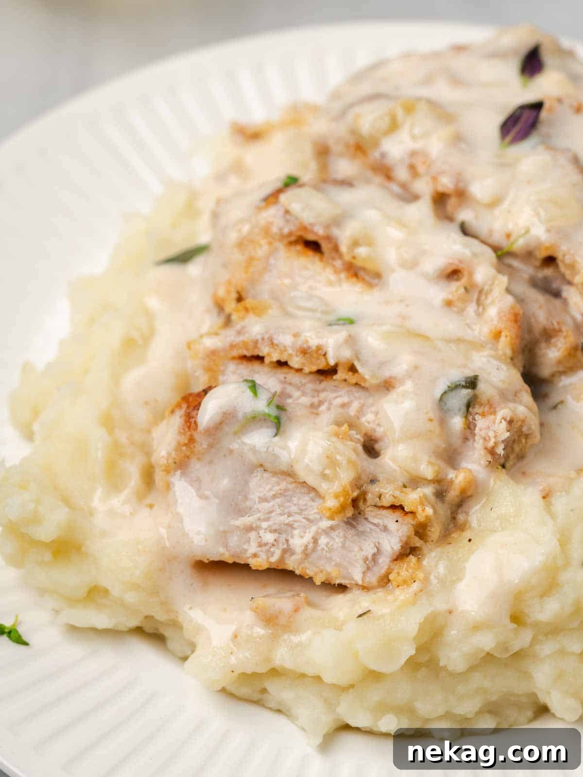 Creamy Mushroom Smothered Pork Chops 3 A perfectly sliced pork chop, served on a bed of creamy mashed potatoes, with savory sauce.